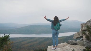 Kadın turist üstte mutlu ve kutluyor başarıdır. Dünya üzerinde bir kot ceket bir kadında muzaffer bir hareketle sevinir
