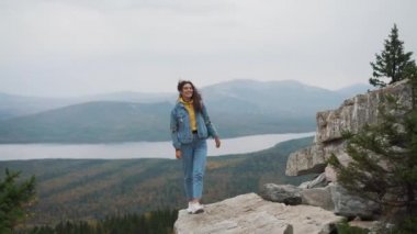 Kadın turist üstte mutlu ve kutluyor başarıdır. Dünya üzerinde bir kot ceket bir kadında muzaffer bir hareketle sevinir