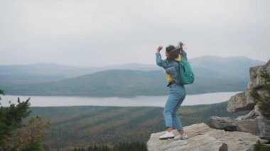 Kadın turist üstte mutlu ve kutluyor başarıdır. Dünya üzerinde bir kot ceket bir kadında muzaffer bir hareketle sevinir