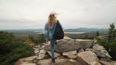 Kadın turist üstte mutlu ve kutluyor başarıdır. Dünya üzerinde bir kot ceket bir kadında muzaffer bir hareketle sevinir