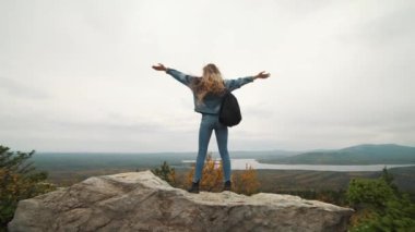 Kadın turist üstte mutlu ve kutluyor başarıdır. Dünya üzerinde bir kot ceket bir kadında muzaffer bir hareketle sevinir