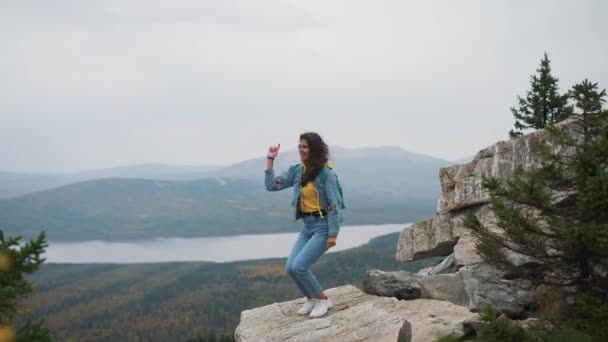 Touristinnen an der Spitze freuen sich und feiern Erfolge. Eine Frau in Jeansjacke auf der Spitze der Welt jubelt über eine siegreiche Geste — Stockvideo