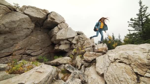 Young woman hiking up the mountain slope wearing leather mountaineering boots. Hiker girl on mountain trekking walking uphill over the sun. — Stock Video