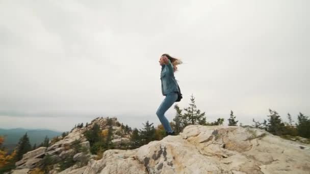 Touristinnen an der Spitze freuen sich und feiern Erfolge. Eine Frau in Jeansjacke auf der Spitze der Welt jubelt über eine siegreiche Geste — Stockvideo