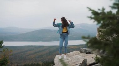 Çekici kadın gülümseyerek ve saçları yüzünü eli ile kapalı tutmaya çalışıyorum rüzgarda üfleme onu uzun saçlı bir dağ tepe üzerinde duran