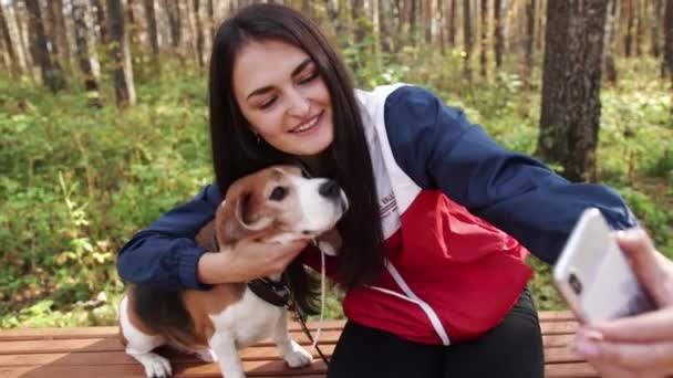 Mujer con un perro encantador paseando en el parque de otoño — Vídeo de stock