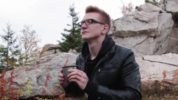 Турист пьет чай из кружки термоса против гор — стоковое видео
