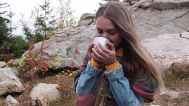 Turista bere il tè da una tazza di un thermos contro le montagne — Video Stock