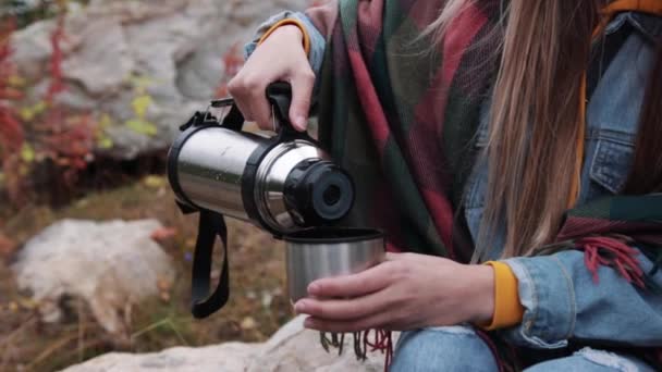 Турист пьет чай из кружки термоса против гор — стоковое видео