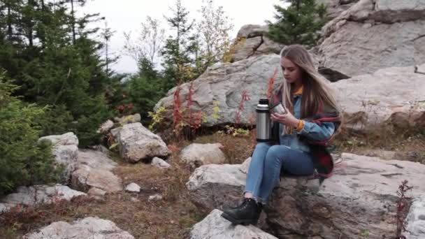 Turista beber té de una taza de un termo contra las montañas — Vídeos de Stock