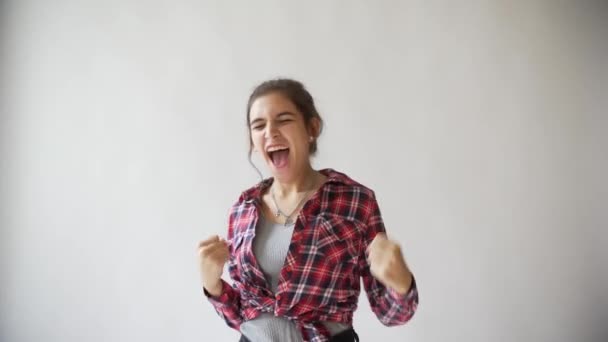 Tanzendes Hipster-Mädchen im karierten Hemd auf hellgrauem Hintergrund. — Stockvideo