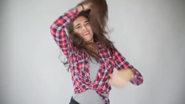 Baile chica hipster en camisa a cuadros sobre fondo gris claro . — Vídeos de Stock