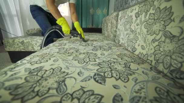 Un homme d'une entreprise de nettoyage qui nettoie le canapé. Homme en uniforme tissu de nettoyage de canapé avec nettoyeur à vapeur sèche . — Video