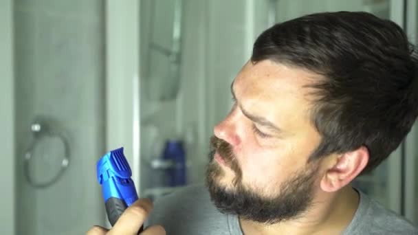 Hombre empezando a afeitarse la barba con máquina de afeitar. — Vídeo de stock