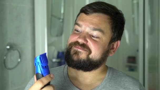 Hombre empezando a afeitarse la barba con máquina de afeitar. — Vídeo de stock