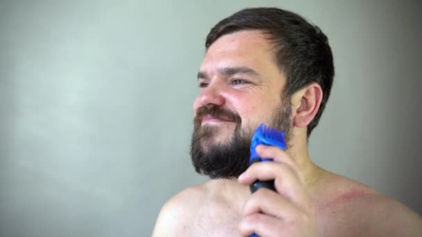 Чоловік починає голити бороду з машиною для бритви . — стокове відео