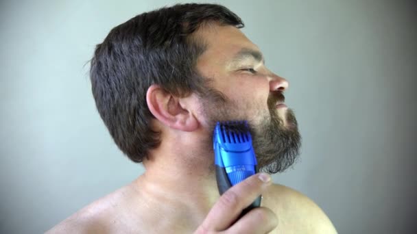 Человек начинает брить бороду с помощью бритвенной машины. — стоковое видео