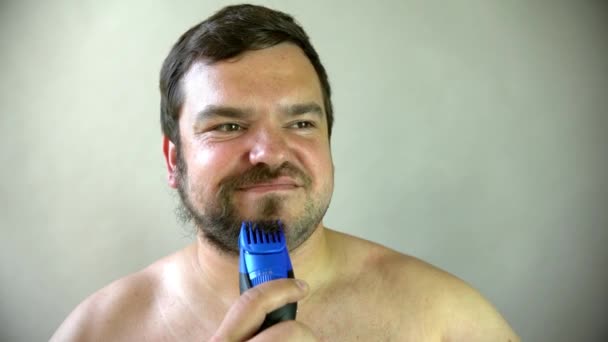 Hombre empezando a afeitarse la barba con máquina de afeitar. — Vídeos de Stock