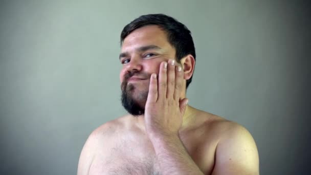Szépség, ápolás és emberek koncepció - fiatal férfi keres tükör és borotválkozó szakálla trimmer vagy elektromos borotva otthon fürdőszoba — Stock videók