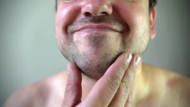 Beleza, aliciamento e conceito de pessoas - jovem olhando para espelho e barba de barbear com aparador ou barbeador elétrico em casa de banho — Vídeo de Stock