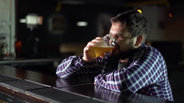 Бородатий чоловік п'є пиво і насолоджується випивкою в паб-барі. Чоловічий гість пробує келих пива — стокове відео