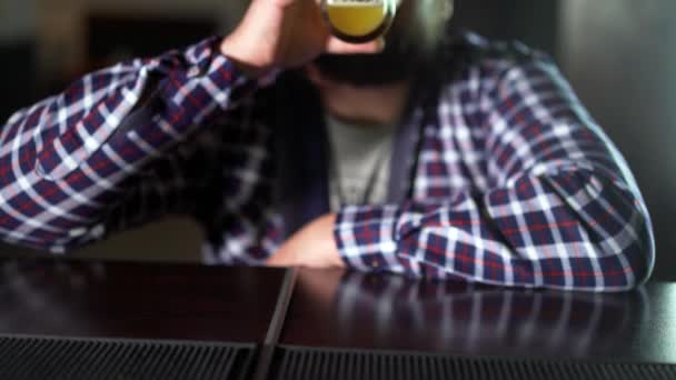 Homem barbudo bebendo cerveja e desfrutando de uma bebida no bar. Masculino convidado tenta um copo de cerveja — Vídeo de Stock