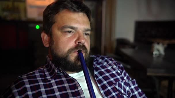 Egy fiatal férfi dohányzik a vízipipa a bárban. — Stock videók