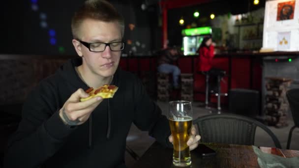 El hombre está comiendo pizza. Tiene un pedazo de pizza en sus manos y come con apetito. . — Vídeos de Stock