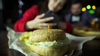Bir kız bir adam fotoğraf üstünde senin smartphone Burger barda çekmek Şirket.