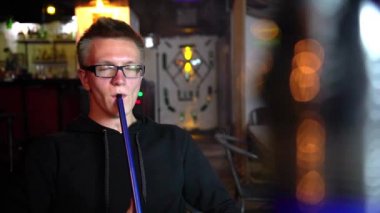 Genç bir adam barda bir nargile sigara içiyor..