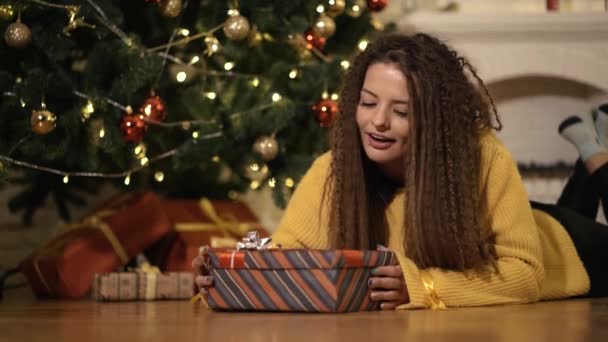 Mujer abre un regalo de año nuevo bajo el árbol de Navidad — Vídeos de Stock
