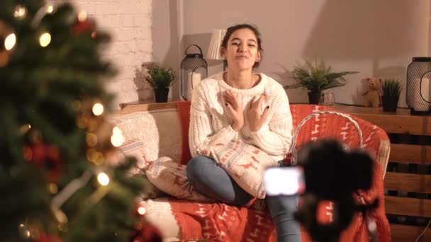 Дівчина-блогер сидить вдома на дивані, розповідає про новий рік і Різдво . — стокове відео