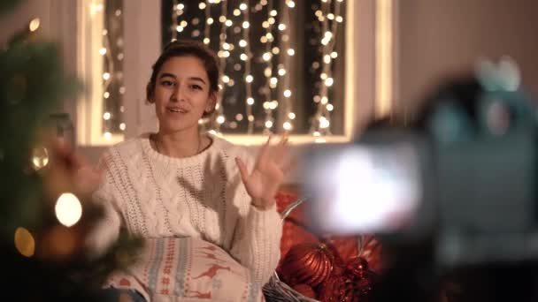 Girl blogger sitter hemma på soffan, talar om nyår och jul. — Stockvideo
