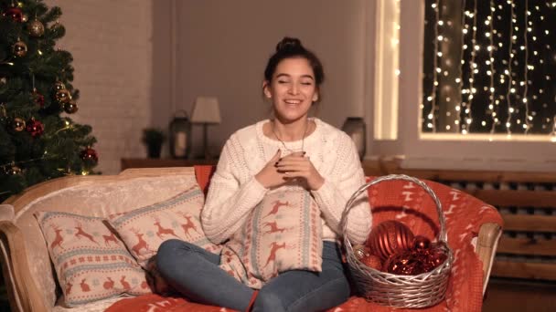 Blogger dziewczyna siedzi w domu na kanapie, opowiada o Boże Narodzenie i nowy rok. — Wideo stockowe