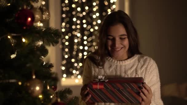 Mulher abre um novo presente de ano sob a árvore de Natal — Vídeo de Stock