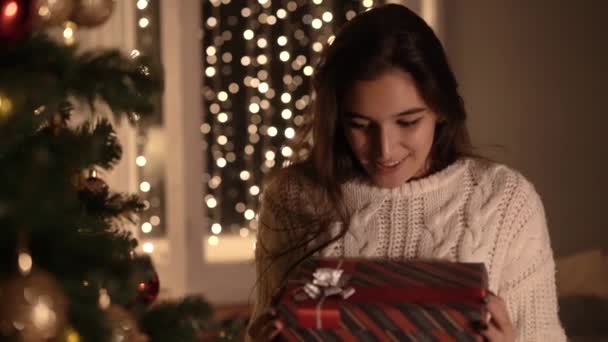 Frau öffnet ein Neujahrsgeschenk unter dem Weihnachtsbaum — Stockvideo