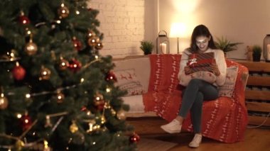Kadın bir yeni yıl hediye Noel ağacının altında açılır
