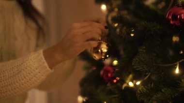 Güzel bir kız kırmızı ve altın top ile Noel ağacı süsle.