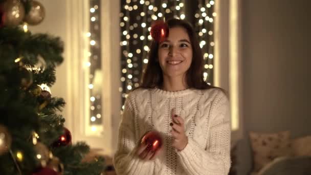 一个漂亮的女孩用红色和金球装饰圣诞树 — 图库视频影像