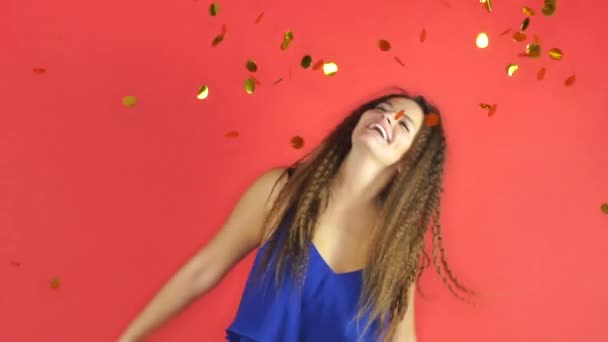 Kvinna som firar nyår på röd bakgrund med gyllene konfetti — Stockvideo