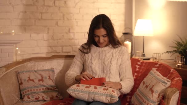 Дівчина бажає і відкриває різдвяний подарунковий пакет. концепція свята та Нового року. дівчина щаслива і посміхається з різдвяним подарунком в її руках . — стокове відео