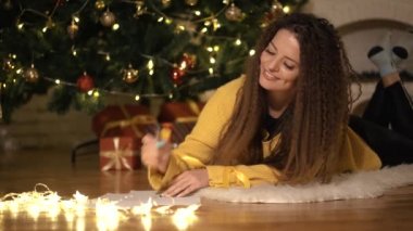 Kız Noel ağacı arka plan üzerinde Noel Baba'ya bir mektup yazar