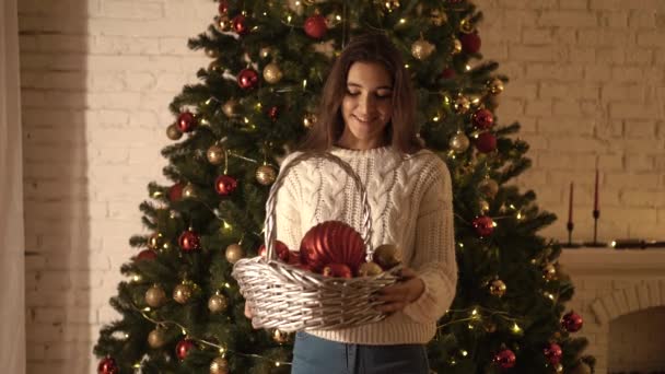 Ein Hübsches Mädchen Schmückt Den Weihnachtsbaum Mit Roten Und Goldenen — Stockvideo