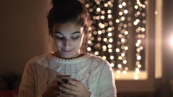 Das Mädchen schreibt an Silvester im Wohnzimmer des Hauses telefonische Nachrichten — Stockvideo