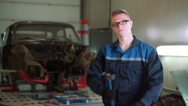 Bir genç güzel araba tamircisi araba atölye, kırık bir araba arka plan olarak portresi. Konsept: makine tamir, tanılamada, uzman onarım, bakım. — Stok video