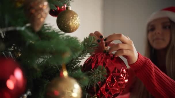 Chica en gorra de Santas decora el árbol de Navidad . — Vídeos de Stock
