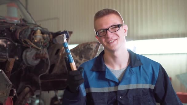 Retrato de un joven mecánico hermoso coche en el taller de coches, en el fondo de un coche roto. Concepto: reparación de la máquina, diagnóstico de fallas, reparación especializada, mantenimiento . — Vídeos de Stock