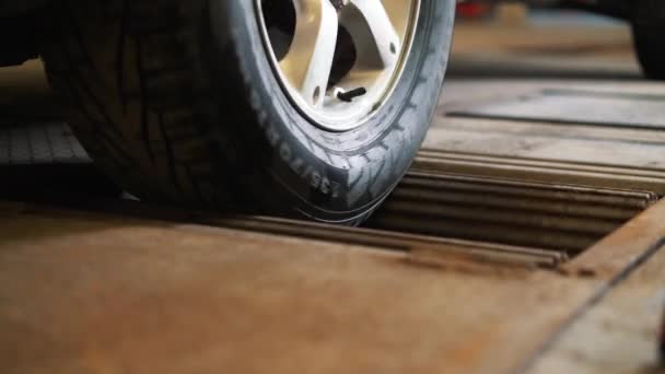 Près de la roue tournante de la voiture au stand pour le diagnostic et la mesure de la puissance de la voiture . — Video