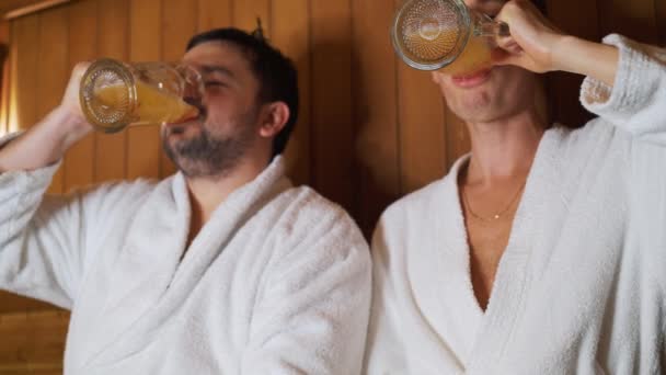 Мужчины отдыхают в бане, сауне, пьют пиво — стоковое видео