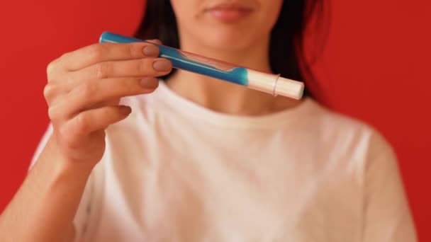 The concept of menstruation, ovulation in girls. Girl on a red background holding a tampon, gasket. — Stock Video